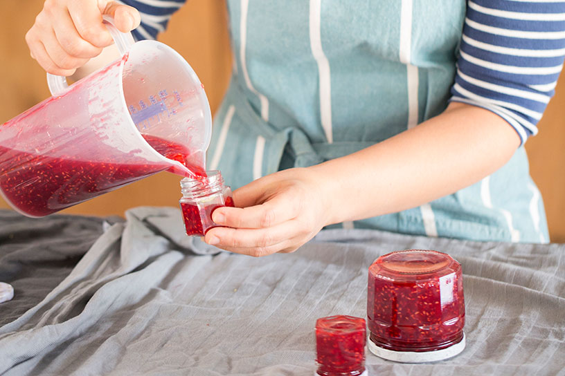 Confituur van frambozen overgieten in kleine potjes